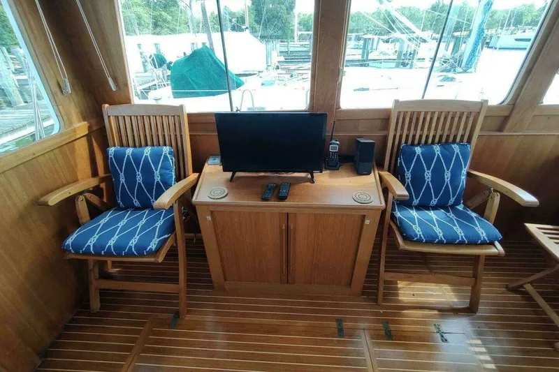Slide: The Image of Interior of 1996 Grand Banks Eastbay 40 Flybridge with wooden chairs and a small TV. - 45