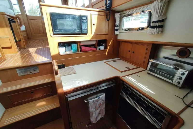 Slide: The Image of 1996 Grand Banks Eastbay 40 Flybridge galley with microwave, oven, and wooden cabinetry. - 50
