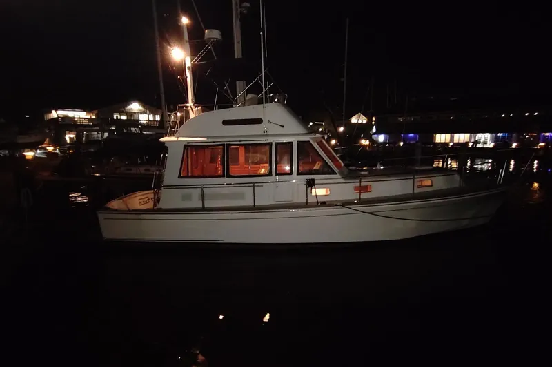 Slide: The Image of 1996 Grand Banks Eastbay 40 Flybridge yacht docked at night, illuminated by harbor lights. - 95