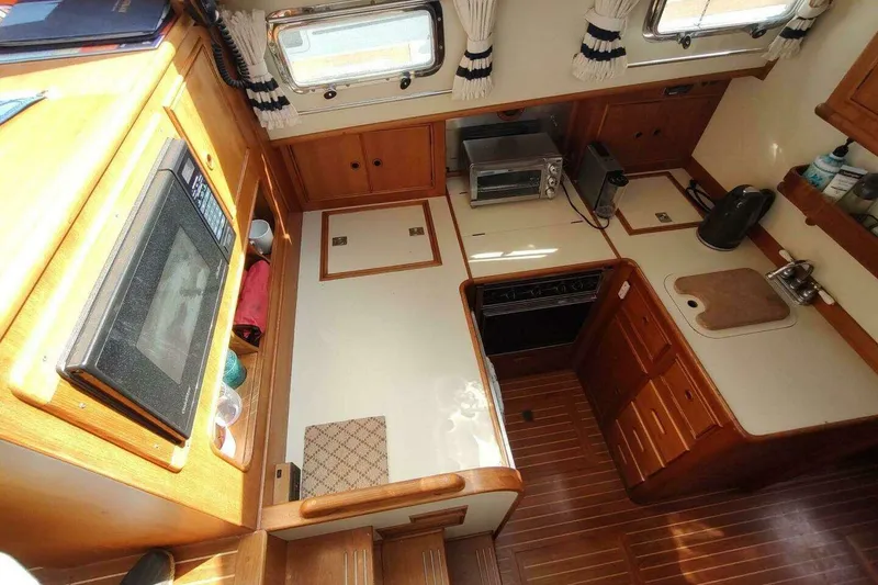 Slide: The Image of 1996 Grand Banks Eastbay 40 Flybridge galley with wood cabinetry, appliances, and natural light. - 49