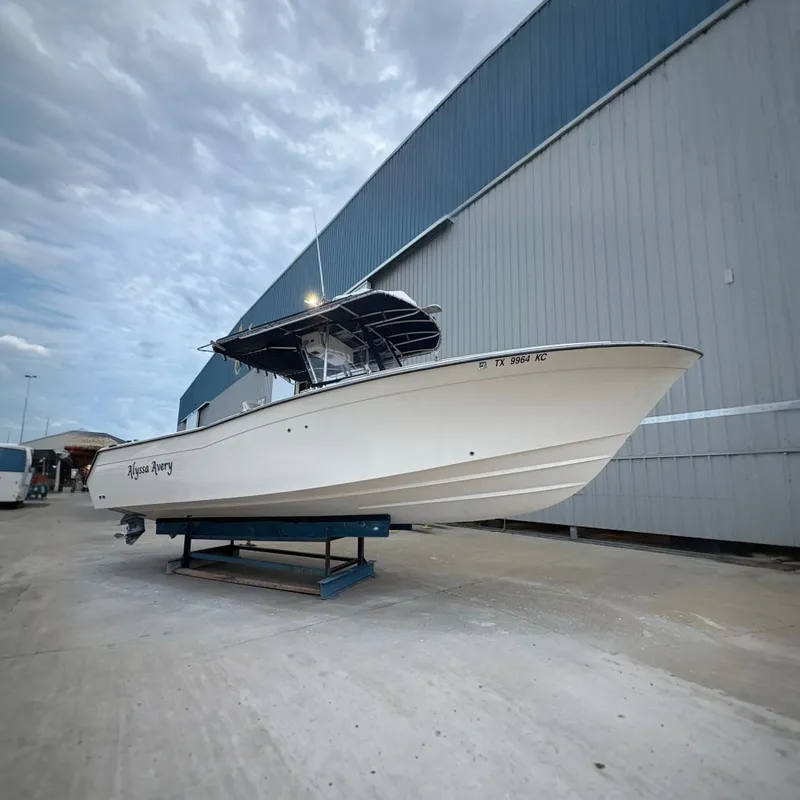 The Image of 2004 Grady White Bimini 306 boat on stand, side view near industrial building. - 0