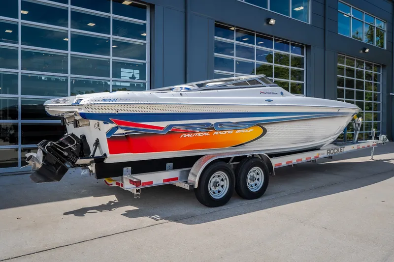 Slide: The Image of 2012 Nautical NRG 30 speedboat on trailer, vibrant design, parked outside modern building. - 61