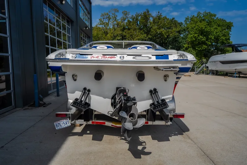 Slide: The Image of Rear view of a 2012 Nautical NRG 30 boat parked outdoors, showcasing its propeller and trim tabs. - 10
