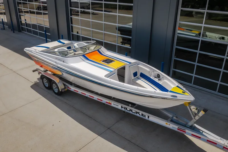 Slide: The Image of 2012 Nautical NRG 30 speedboat on trailer, vibrant design, parked outside a modern building. - 6