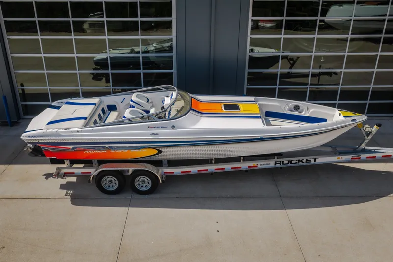 Slide: The Image of 2012 Nautical NRG 30 speedboat on trailer, vibrant design, parked outside garage. - 54