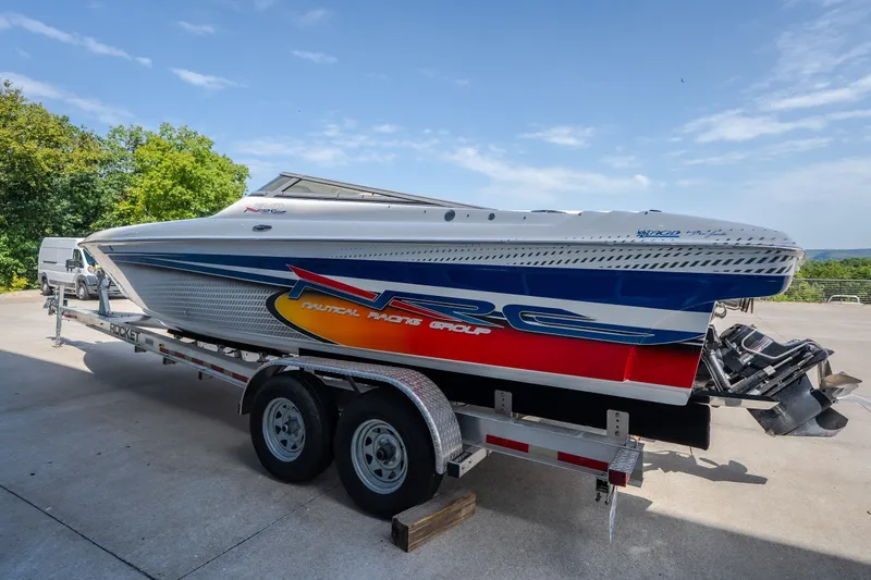 Slide: The Image of 2012 Nautical NRG 30 speedboat on trailer, vibrant graphics, parked outdoors. - 47