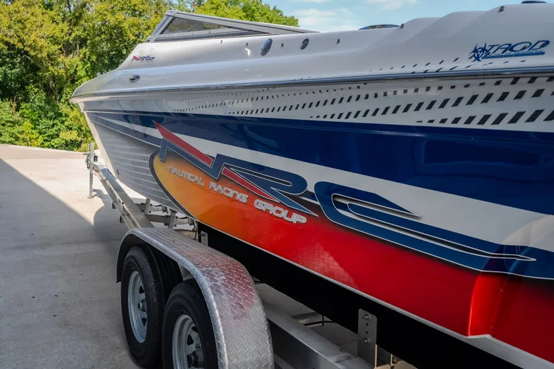 Slide: The Image of 2012 Nautical NRG 30 boat on trailer, featuring vibrant red and blue design. - 56