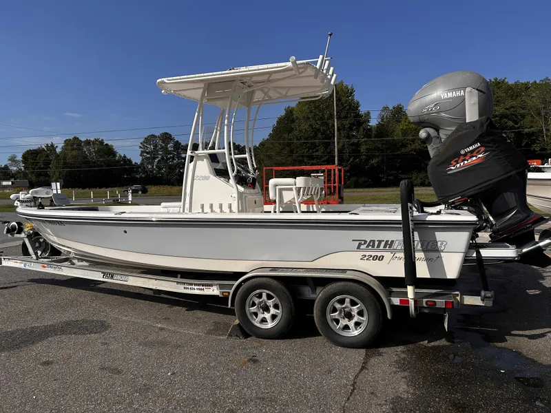 The Image of A white 2020 Pathfinder 2200 Tournament XL boat on a trailer. It features a T-top and Yamaha outboard motor. - 1