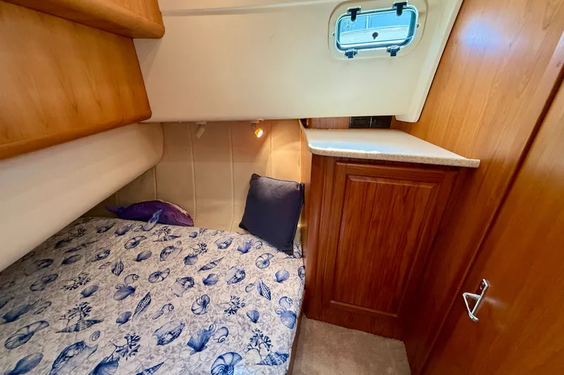 Slide: The Image of Cozy cabin interior of 1999 Mainship 350 Trawler with nautical-themed bedding. - 44