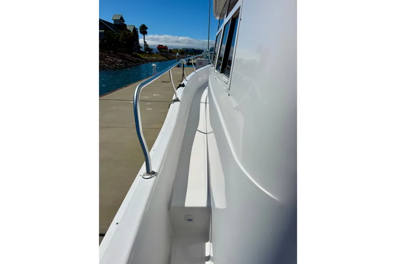 Slide: The Image of Side view of 1999 Mainship 350 Trawler docked, showcasing sleek white exterior and railing. - 52