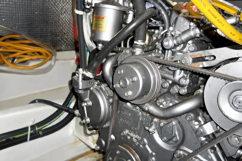 Slide: The Image of Engine compartment of a 1999 Mainship 350 Trawler, showcasing mechanical components and belts. - 56