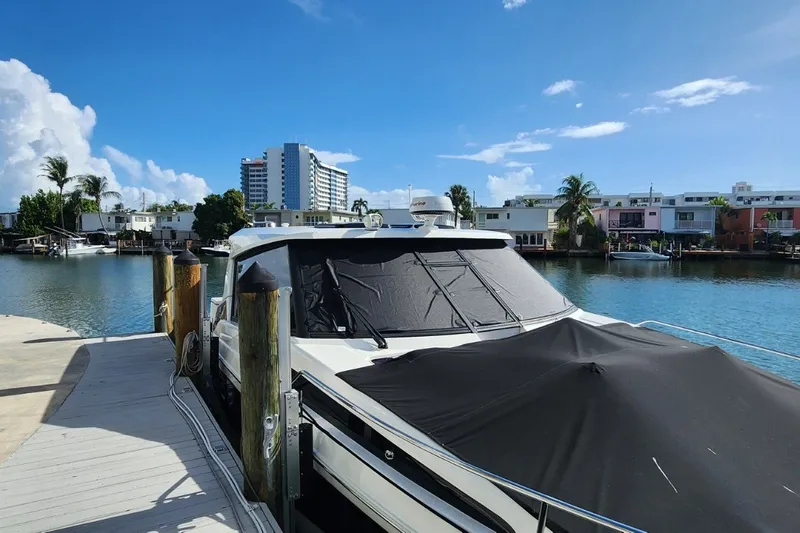 Slide: The Image of 2024 Aquila 36 Sport yacht docked by waterfront homes under a clear blue sky. - 17