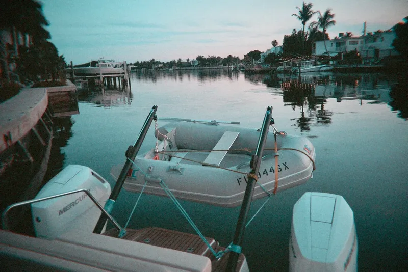 Slide: The Image of Aquila 36 Sport 2024 with dinghy on calm waterfront at sunset. - 26