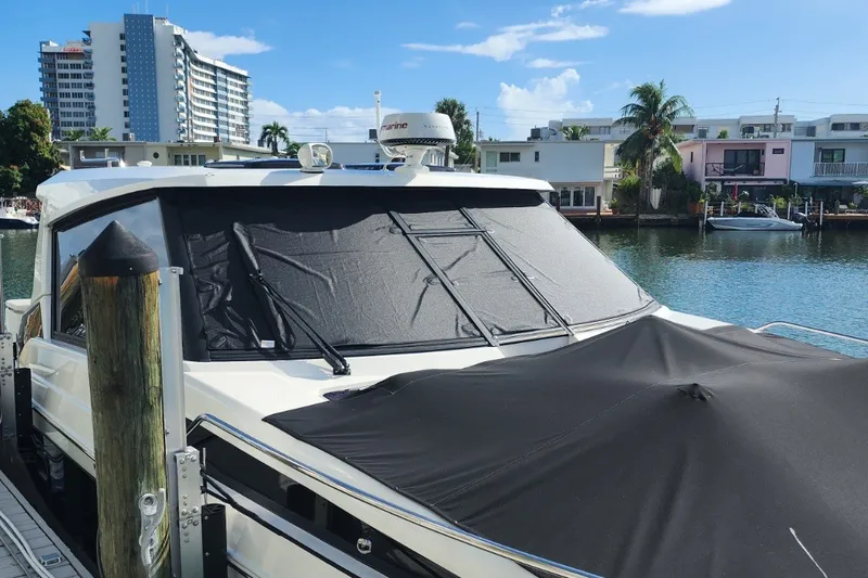 Slide: The Image of 2024 Aquila 36 Sport yacht docked by waterfront homes under clear blue sky. - 20