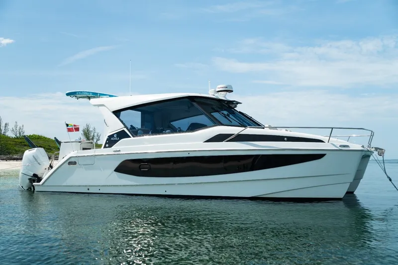 The Image of 2024 Aquila 36 Sport boat anchored in clear water under a blue sky. - 1