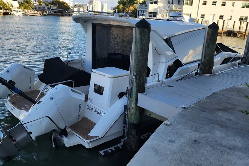 Slide: The Image of 2024 Aquila 36 Sport docked, featuring dual Mercury outboard engines, in a serene marina setting. - 22