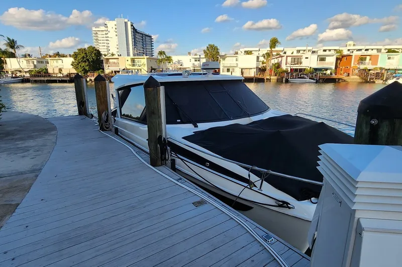 Slide: The Image of 2024 Aquila 36 Sport yacht docked by waterfront homes under a blue sky. - 16