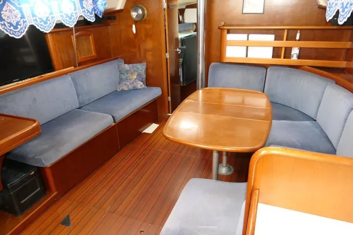 Slide: The Image of Interior of 1999 Beneteau 411 sailboat with wooden table and blue seating. - 4