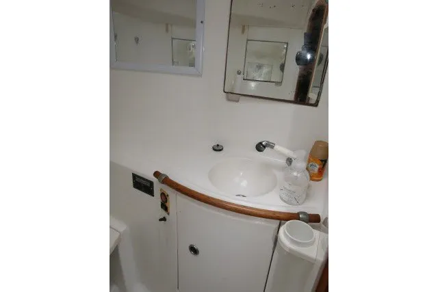 Slide: The Image of Bathroom sink area in a 1999 Beneteau 411 yacht, featuring a mirror and faucet. - 40