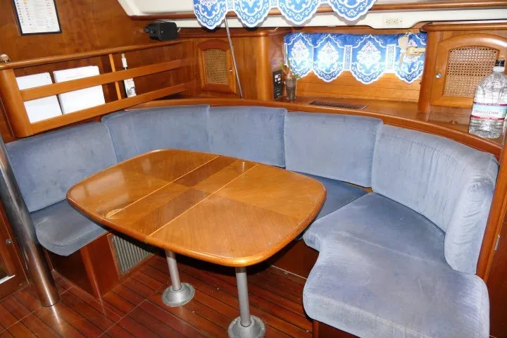 Slide: The Image of Interior of 1999 Beneteau 411 yacht with wooden table and blue cushioned seating. - 9