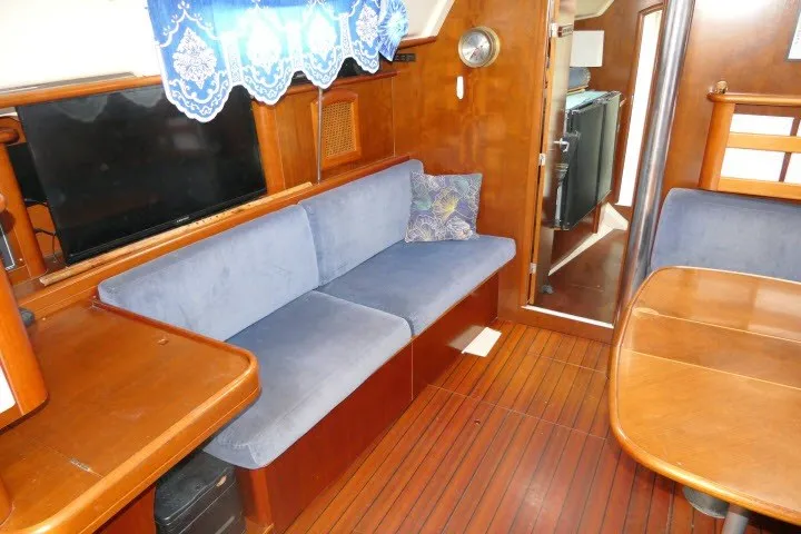 Slide: The Image of Interior of 1999 Beneteau 411 yacht with blue seating, wooden flooring, and dining area. - 6