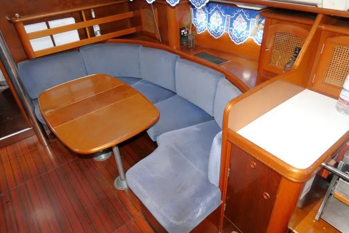 Slide: The Image of Interior of 1999 Beneteau 411 yacht with blue seating and wooden table. - 10