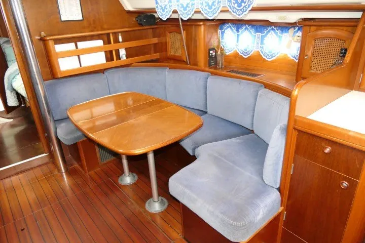 Slide: The Image of Interior of 1999 Beneteau 411 yacht with wooden dining table and blue cushioned seating. - 8
