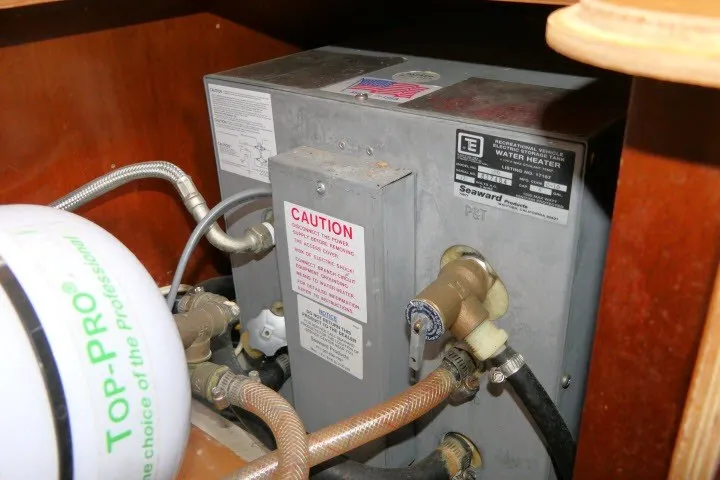 Slide: The Image of Water heater system in a 1999 Beneteau 411 yacht, featuring caution labels and plumbing connections. - 73