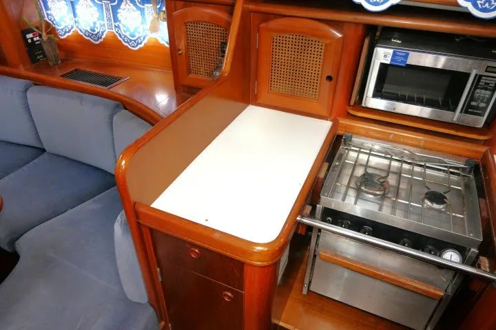 Slide: The Image of Interior of a 1999 Beneteau 411 yacht featuring a compact kitchen with stove and microwave. - 15