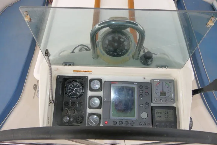 Slide: The Image of Cockpit controls of a 1999 Beneteau 411 sailboat, featuring navigation instruments and compass. - 52