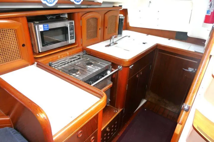 Slide: The Image of 1999 Beneteau 411 yacht kitchen with stove, microwave, and wooden cabinetry. - 14