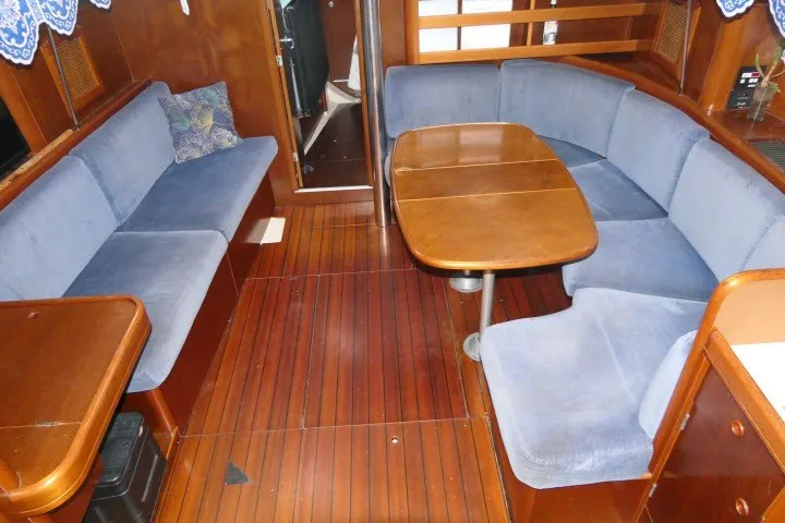Slide: The Image of Interior of 1999 Beneteau 411 sailboat with blue seating and wooden table. - 3