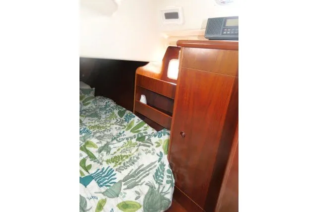 Slide: The Image of Interior cabin of 1999 Beneteau 411 sailboat with wooden cabinetry and floral bedding. - 28