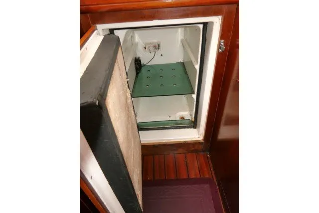 Slide: The Image of Open refrigerator inside a 1999 Beneteau 411 yacht, showcasing wooden interior. - 19