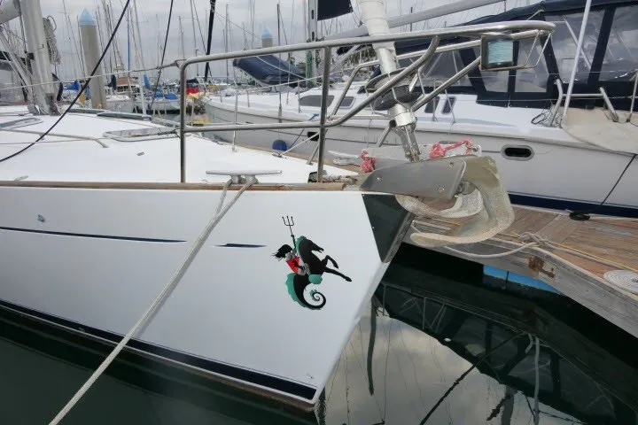 Slide: The Image of Sailboat Beneteau 411 (1999) docked, featuring a unique seahorse and trident design on the bow. - 76
