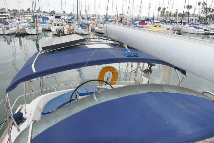 Slide: The Image of 1999 Beneteau 411 sailboat docked in marina, featuring blue canopy and visible mast. - 58