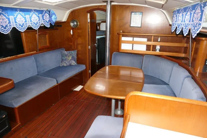 Slide: The Image of Interior of a 1999 Beneteau 411 sailboat with blue seating and wooden finishes. - 2