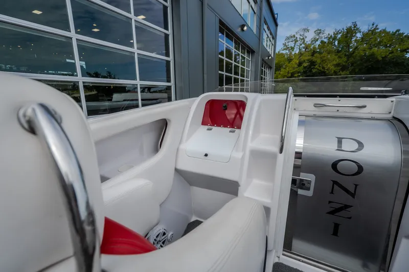 Slide: The Image of 2005 Donzi 35 ZR boat interior with sleek white and red seating, docked near modern building. - 30