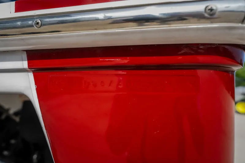 Slide: The Image of Close-up of a 2005 Donzi 35 ZR boat's red and white hull with chrome detailing. - 47