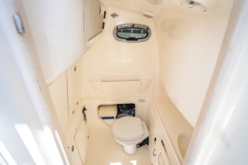 Slide: The Image of Interior of 2006 Boston Whaler 320 Outrage boat bathroom with toilet and storage. - 24