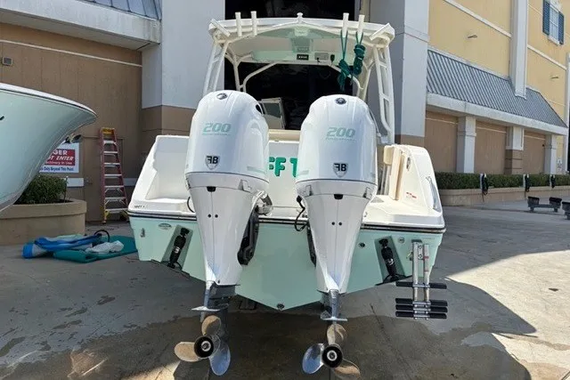 Slide: The Image of 2021 Century 24 Resorter boat with twin 200 HP outboard engines, docked outdoors. - 20