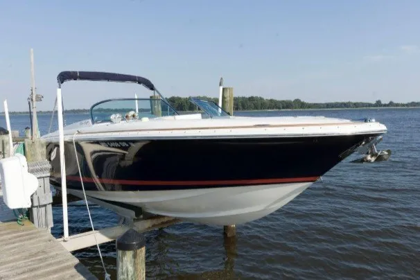 The Image of 2005 Chris-Craft Launch 28 boat docked on a serene lake under clear skies. - 0
