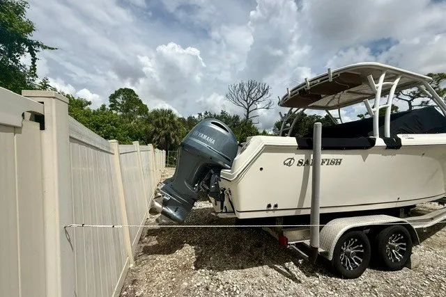 Slide: The Image of 2015 Sailfish 276 DC boat on trailer with Yamaha engine, parked near a fence. - 4