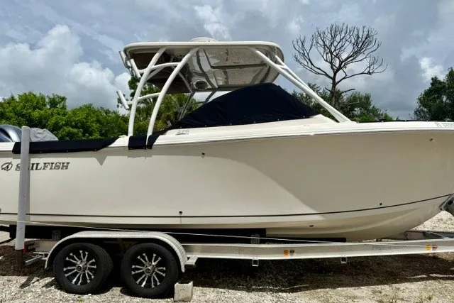 Slide: The Image of 2015 Sailfish 276 DC boat on trailer, side view, under cloudy sky. - 1