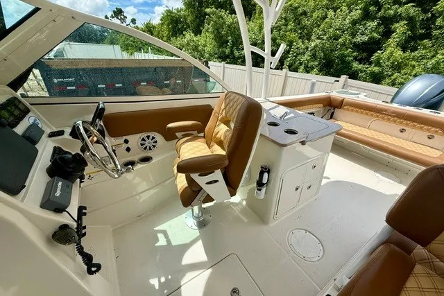Slide: The Image of 2015 Sailfish 276 DC boat interior with tan seating and modern controls. - 12