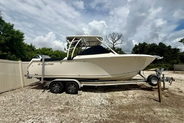 The Image of 2015 Sailfish 276 DC boat on trailer, parked outdoors under cloudy sky. - 0