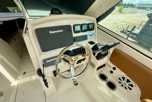 Slide: The Image of 2015 Sailfish 276 DC boat dashboard with Raymarine electronics and steering wheel. - 13