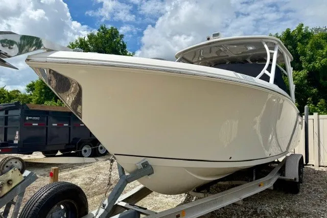 Slide: The Image of 2015 Sailfish 276 DC boat on trailer under a partly cloudy sky. - 3