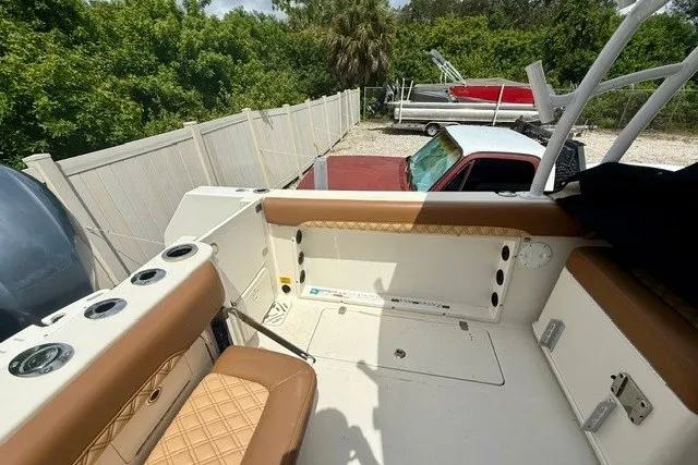 Slide: The Image of 2015 Sailfish 276 DC boat interior with tan seating, cup holders, and storage compartments. - 8