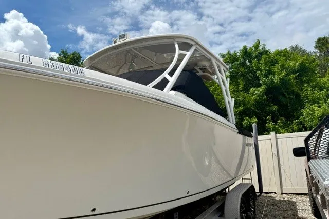 Slide: The Image of 2015 Sailfish 276 DC boat on trailer, parked outdoors under a partly cloudy sky. - 2
